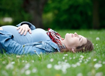 Beautiful pregnant woman relaxing on grass